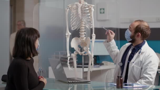 Health specialist pointing at human skeleton to explain osteopathy — Stock Video