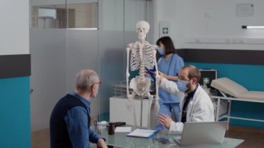 Osteopati uzmanı teşhis koymak için insan iskeleti kullanıyor.