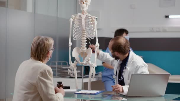 Physician pointing at human skeleton to explain osteopathy diagnosis — Stock Video