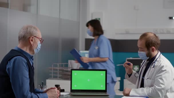 Oudere man op zoek naar greenscreen op laptop met arts — Stockvideo