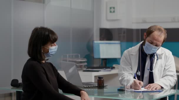 医師がメモを取り、女性患者に処方紙を与える — ストック動画