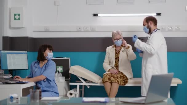 Отоларинголог консультує старшу жінку з використанням медичного отоскопа — стокове відео