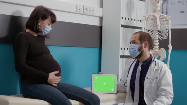 Kobieta z brzuchem ciąży patrząc na zielony szablon ekranu — Wideo stockowe