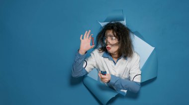 Aptal bilim adamı kamerada sırıtıyor ve test tüplerini gösteriyor.