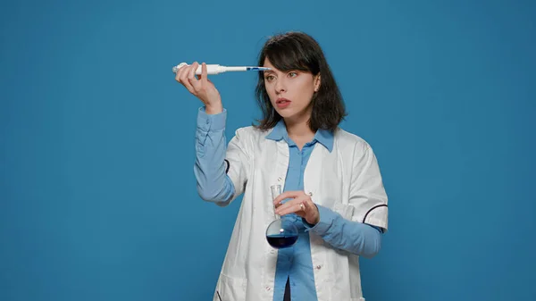 Mujer científica usando micro pipeta para gotear líquido en vaso de precipitados — Foto de Stock