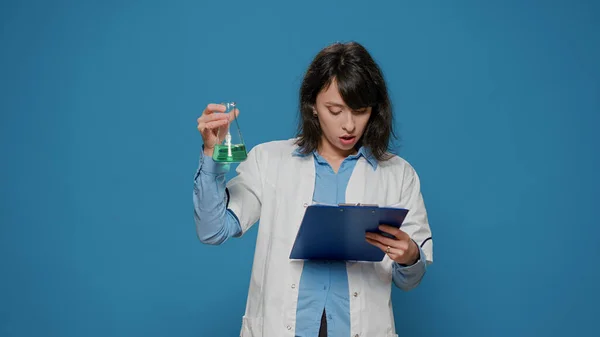 Kadın bilim adamı deney tüpü ve kimya dosyalarındaki sıvıyı analiz ediyor. — Stok fotoğraf