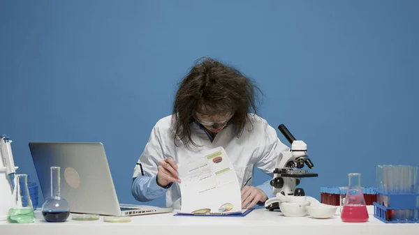 Goofy científico loco utilizando el ordenador portátil y documentos en la cámara —  Fotos de Stock