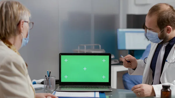 Äldste person tittar på greenscreen på laptop vid checkup besök — Stockfoto