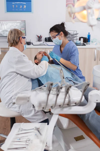 Команда стоматологов с медицинскими масками для лица с использованием профессиональных стоматологических инструментов — стоковое фото