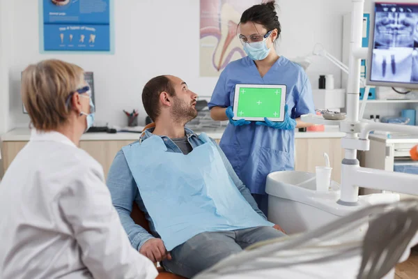 Стоматолог-жінка тримає сміх вгору зелений екран хром ключ планшет — стокове фото