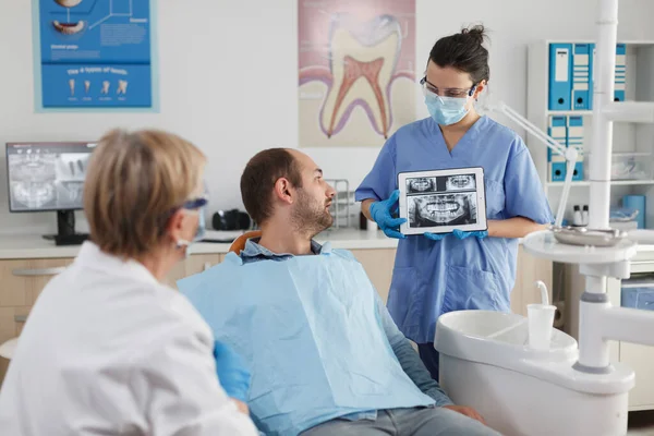 Медсестра-стоматолог в маске для лица с планшетным компьютером — стоковое фото