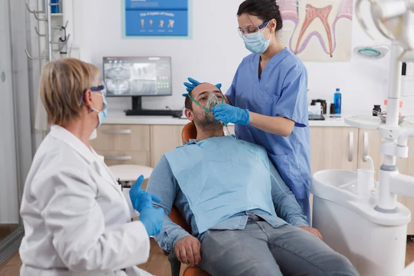 Больной пациент сидит на стоматологическом стуле во время консультации стоматолога — стоковое фото