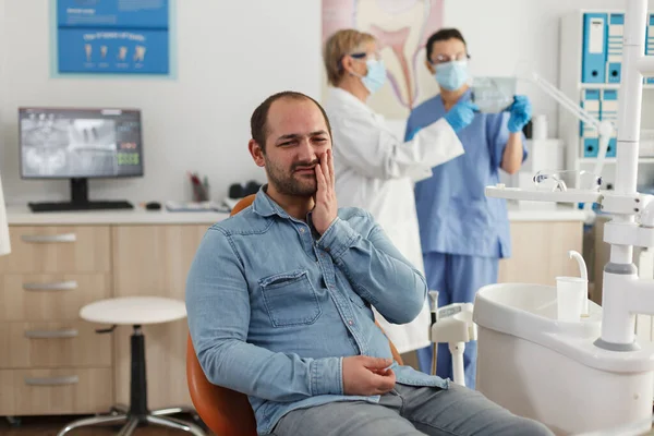 Porträtt av man patient med tänder smärta sitter på tandstolen — Stockfoto