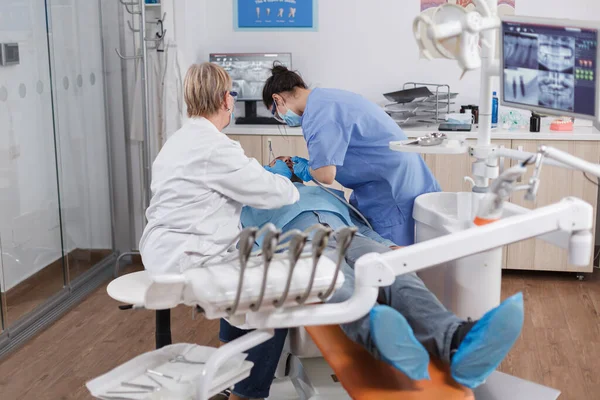 Orthodontist team opereert patiënt met cariës met behulp van tandheelkundige hulpmiddelen — Stockfoto