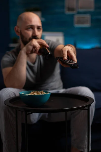 Man drinking beer and searching movie on television