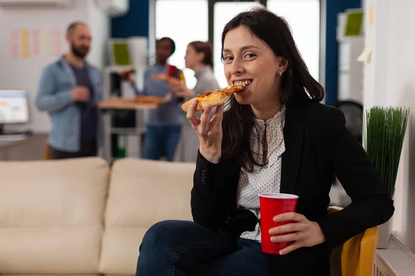Retrato de mulher comendo pizza após o horário de trabalho na festa — Fotografia de Stock