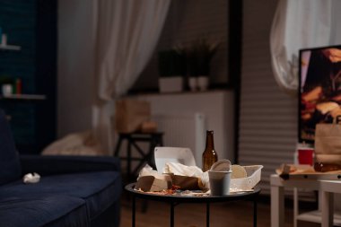 Oturma odasında çöp tenekesi ve yemek artıklarıyla kimse oturmuyor.