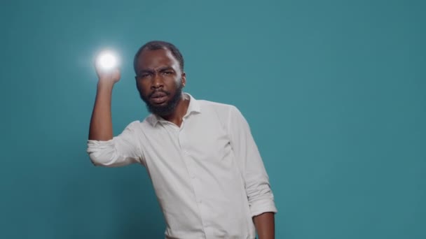 Испуганный человек использует фонарь, чтобы сделать свет и оглянуться вокруг — стоковое видео