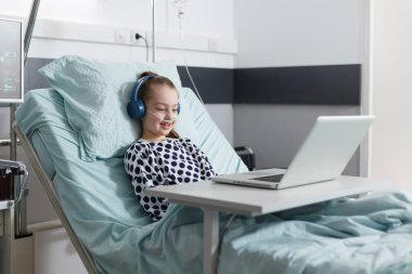 Hasta küçük kız hastane yatağında dinlenirken çocuklar için komik çizgi filmler izliyor..