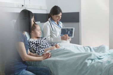 Pediyatri hastanesi radyoloji uzmanı hasta kızın röntgen sonuçları hakkında konuşuyor..