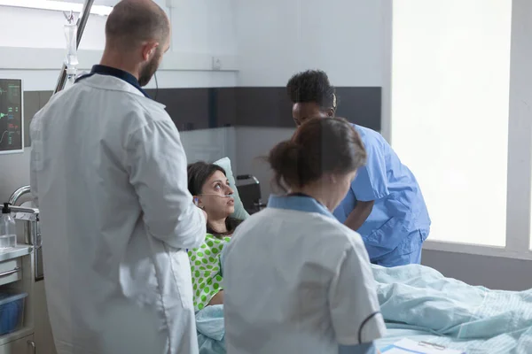 Paciente ingresado en el hospital recuperándose en cama recibiendo atención médica profesional de una enfermera experimentada —  Fotos de Stock