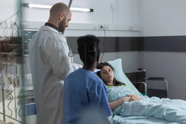 Lékař a zdravotní sestra dělat konzultace v soukromém oddělení na zotavující se ženy v nemocniční posteli — Stock fotografie