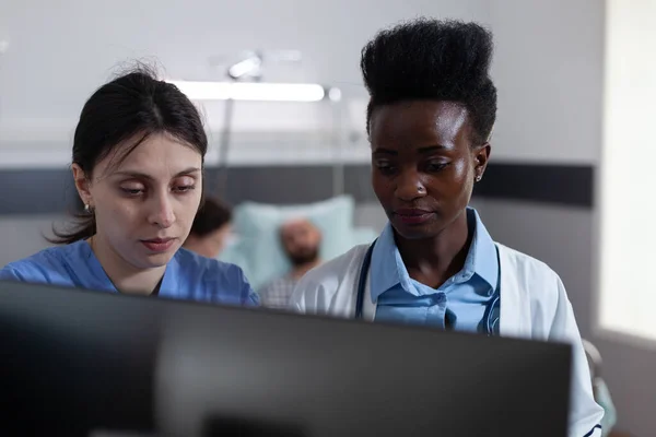 Νοσοκόμα και αφροαμερικανός γιατρός που χρησιμοποιεί τον προσωπικό υπολογιστή για την κλινική εικόνα — Φωτογραφία Αρχείου