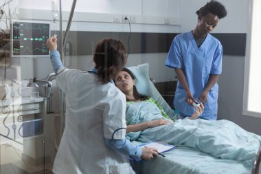 Hemşire hasta parmağına nabız oksimetresi yerleştirirken doktor merkezi damar yolu kategorisini hazırlıyor.