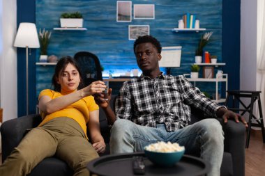 Afrikalı Amerikalı bir adam hamile bir beyaz kadına bir bardak su veriyor.