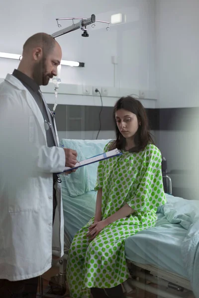 Femme déprimée dans le lit d'hôpital découvre qu'elle a une maladie grave du médecin tenant presse-papiers — Photo