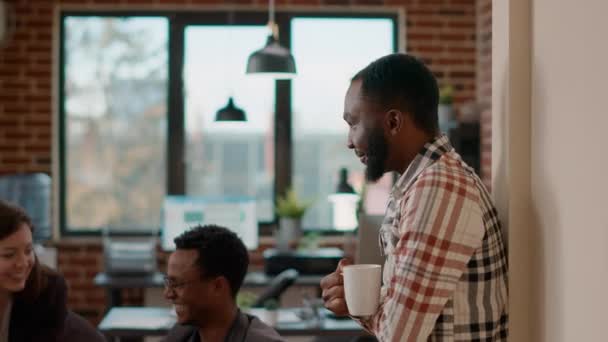 Afroamerikansk man skrattar och pratar med arbetskamrater — Stockvideo