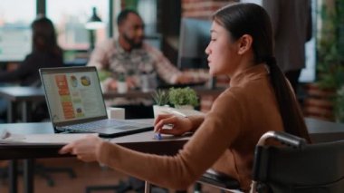 Özürlü bir ofis çalışanı bilgisayardaki iş çizelgelerini analiz ediyor.