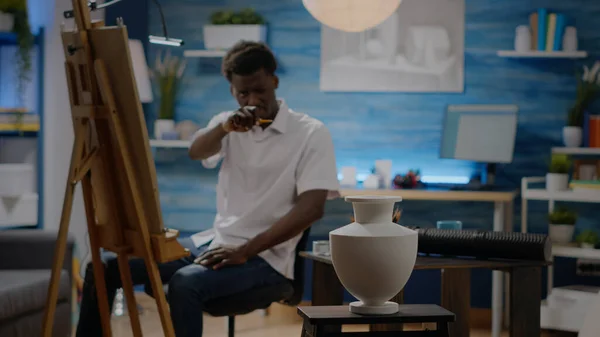 Yaratıcı proje için siyah genç adam vazo çiziyor. — Stok fotoğraf