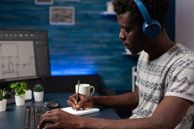 Kulaklık takan tasarımcı emlak planlarını analiz ediyor.