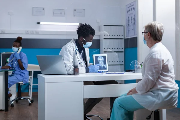 Specialista in radiologia che spiega l'immagine della scansione a raggi X al paziente anziano — Foto Stock