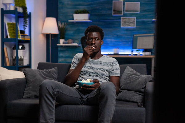 Relaxed young adult resting on couch watching football game