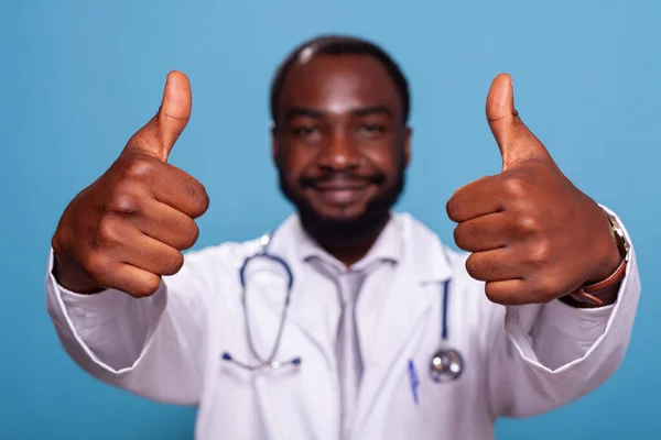 Closeup of hands giving thumbs up of cheerful african american doctor — Stock Photo, Image
