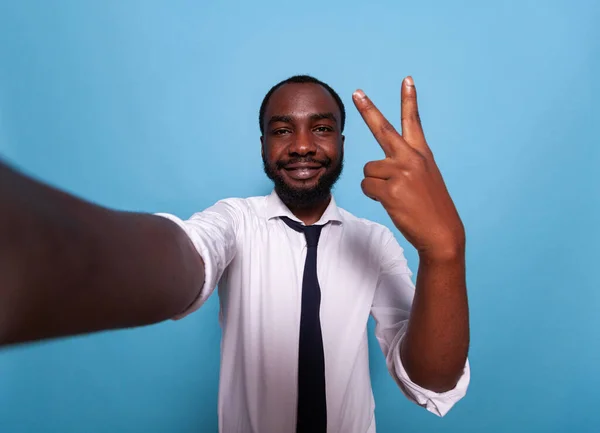 Vlogger sonriente mostrando el signo de paz en la cámara en la conferencia de videocall —  Fotos de Stock