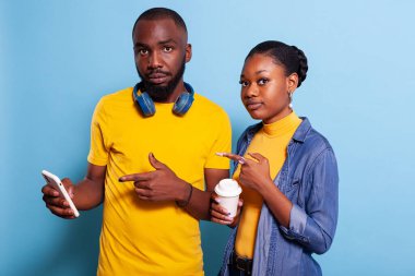 Afrikalı Amerikalı aşıklar stüdyodaki akıllı telefon ekranını işaret ediyorlar.