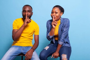 Erkek ve kadın parmakları ağızda gizli işaret veriyorlar.