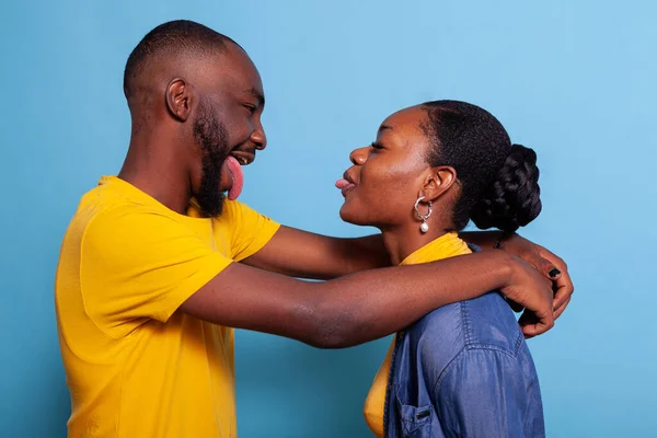 Silly couple embracing and sticking tongue out at each other — Stock Photo, Image