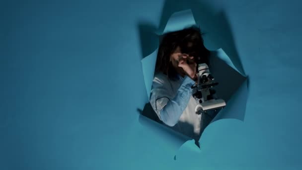 Безумный глупый ученый использует лабораторный микроскоп в студии — стоковое видео