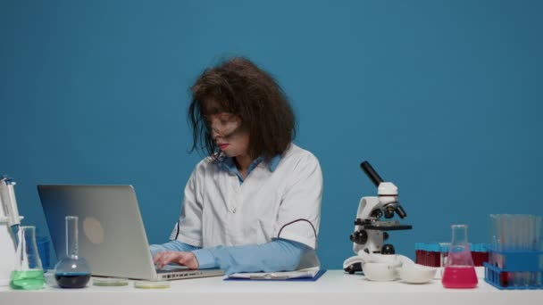 Сумасшедший ученый использует ноутбук и документы на камеру — стоковое видео