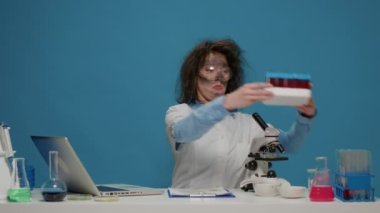 Saçları dağınık, test tüplerine bakan komik çılgın bilim adamı.