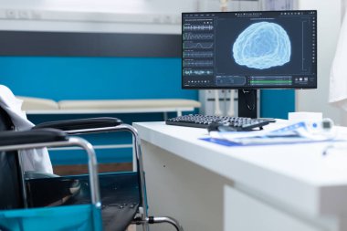 Bilgisayar masada duruyor ve ekranda beyin tomografisi var.