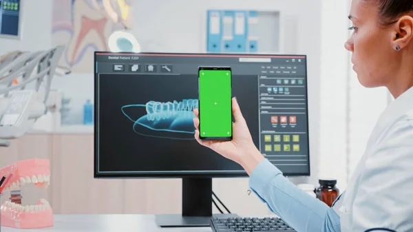 Femme travaillant comme dentiste avec écran vert sur smartphone — Photo