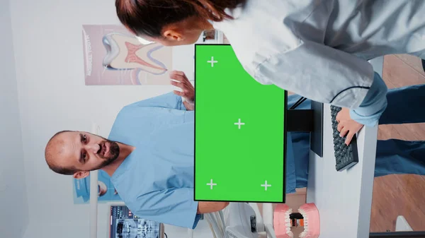 Vertikální video: Zubař pracující s horizontálně zelenou obrazovkou — Stock fotografie