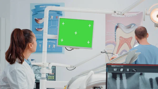 Команда стоматологов работает с зеленым экраном на компьютере — стоковое фото