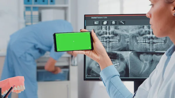 緑の画面でスマートフォンを分析する歯科医のクローズアップ — ストック写真