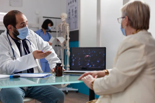 Doctor and pensioner looking at virus illustration on laptop — Stock Photo, Image